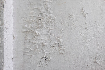 Close-up texture of a damaged white wall with cracked and peeling paint. Perfect for construction, renovation, or interior design backgrounds.
