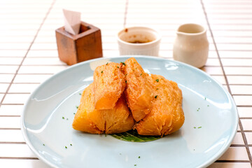 Golden fried cassava served on a light blue plate with white background. Perfect for restaurant menu design, tropical food promotion, or culinary asia traditional snacks.