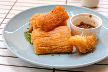 Golden fried cassava served on a light blue plate with white background. Perfect for restaurant menu design, tropical food promotion, or culinary asia traditional snacks.