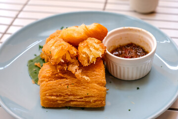 Golden fried cassava served on a light blue plate with white background. Perfect for restaurant menu design, tropical food promotion, or culinary asia traditional snacks.