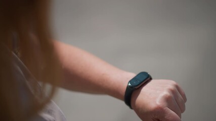 Top close up of white lady tapping smartwatch screen outdoors under sunlight, reflection on display showing focus and interaction, capturing concept of modern lifestyle and wearable technology - Powered by Adobe