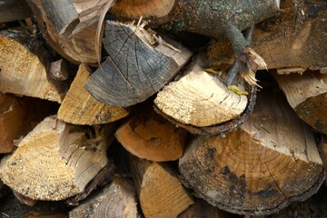 Pile of firewood neatly stacked beside the wall of a house in natural condition. Rural lifestyle and winter preparation concept.