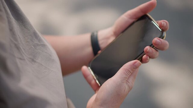Close up of woman holding smartphone outdoors, looking at photo on screen before pressing it to chest, sunlight reflecting on glass surface, capturing emotion of longing
