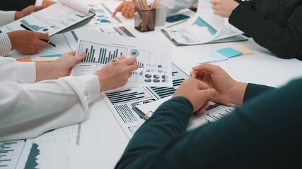 A dynamic business meeting showcasing collaboration among professionals analyzing data visualizations with charts and graphs at a modern conference table. SACTR - Powered by Adobe