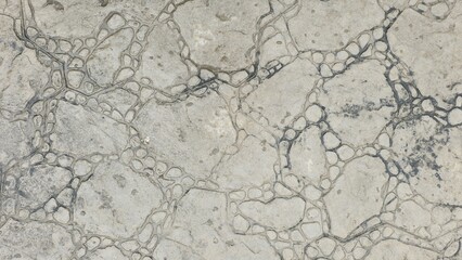 The old grey stone floor has natural cracks and irregular patterns. It is damp from light rain, giving it a dark and wet texture, suitable for use as a background or pattern.