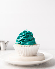 blue frosting on cupcakes with a white background, cupcakes in white liners with tall buttercream swirl, blue buttercream frosted cupcakes on a white background