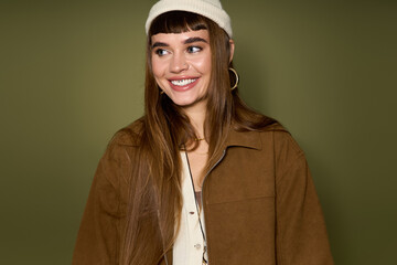 Bright smile of a young woman in stylish casual wear against a green background