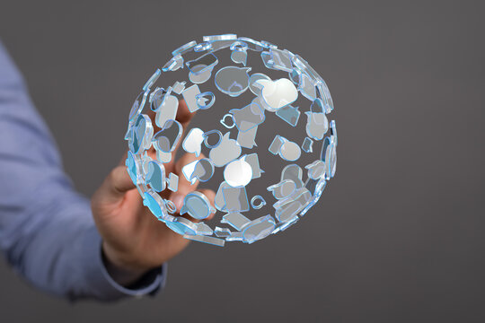 Abstract image of a hand holding a transparent globe made up of speech bubbles, representing communication, social media, and global