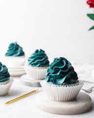blue frosting on cupcakes with a white background, cupcakes in white liners with tall buttercream swirl, blue buttercream frosted cupcakes on a white background