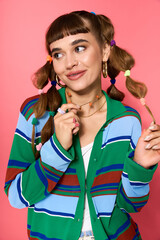 Stylish young woman posing playfully against a vibrant pink background © Bliss