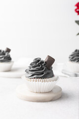 grey frosting on cupcakes with a white background, cupcakes in white liners with tall buttercream swirl, grey buttercream frosted cupcakes on a white background