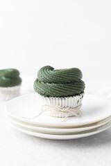 green frosting on cupcakes with a white background, cupcakes in white liners with tall buttercream swirl, green buttercream frosted cupcakes on a white background