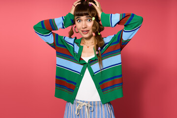 Young woman expressing joy in stylish outfit against vibrant pink backdrop