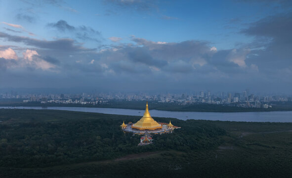 Aerial view of the serene Global Vipassana Pagoda gleaming golden against the backdrop of Mumbai's skyline and the Arabian Sea, Borivali Gorai, Mumbai, Maharashtra, India.
