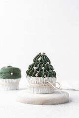 green frosting on cupcakes with a white background, christmas tree cupcakes in white liners with tall buttercream swirl, christmas green buttercream frosted cupcakes on a white background