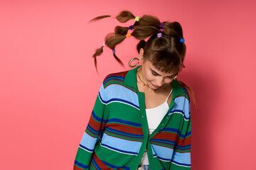 Young womans stylish look with playful hairstyle against a vibrant pink backdrop