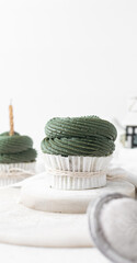 green frosting on cupcakes with a white background, cupcakes in white liners with tall buttercream swirl, green buttercream frosted cupcakes on a white background