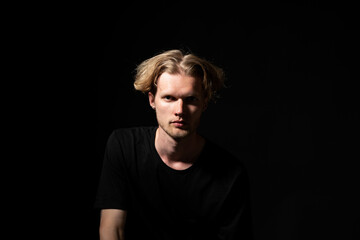 Obraz premium Confident man in black shirt looking forward in low key portrait with focused expression