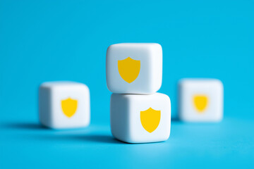 Three white cubes with yellow shield icons stacked on a bright blue surface, symbolizing security and protection.