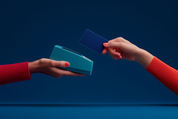 A hand presents a card to another hand holding a sleek payment device, set against a deep blue background, symbolizing modern transactions.