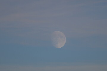 full moon visible in blue daytime sky