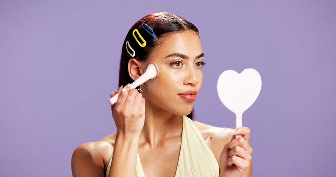 Makeup, mirror and brush woman in studio for cosmetics, contour and beauty maintenance. Self care, glow and blush tools with person on purple background for highlighter shine, foundation and gen z