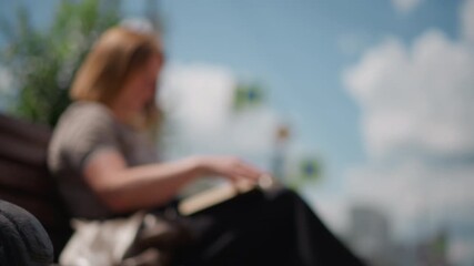 Lady reading outdoors turning page of open book under soft natural light, calm and peaceful atmosphere captured in subtle motion with warm tones and smooth gradient