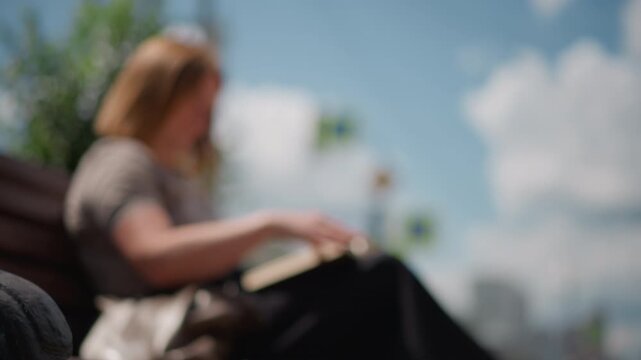 Lady reading outdoors turning page of open book under soft natural light, calm and peaceful atmosphere captured in subtle motion with warm tones and smooth gradient