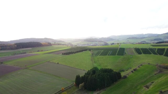 rohnenflug &uuml;ber herbstliche Felder und Wiesen in Nordhessen &ndash; Blick auf Mischwald, H&uuml;gel und D&ouml;rfer im Abendlicht, untergehende Sonne und Feldwege in idyllischer Mittelgebirgslandschaft