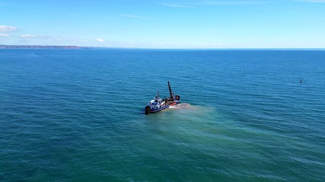 Teignmouth, South Devon, England: DRONE VIEWS: A dredger dredges sand and gravel close to the River Teign estuary; constant dredging ensures the unhindered passage of shipping to Teignmouth's port.