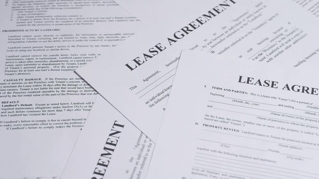 Paper lease agreement forms. Rental agreement paperwork. Top view. Rotation. Document is mock-up