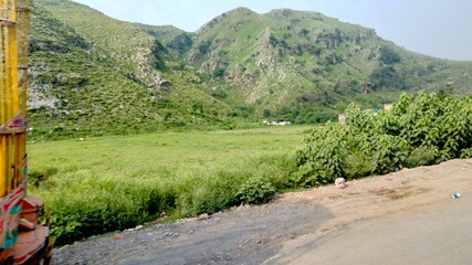 Lush green valley nestled between majestic, sun-drenched mountains under a clear sky.