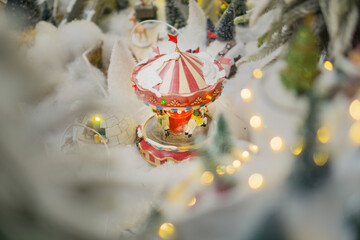 miniature Christmas carousel covered in fake snow with soft bokeh lights in a winter village display concept of holiday decoration, festive retail, seasonal entertainment