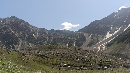 Majestic mountain valley landscape with rocky slopes and sparse vegetation under a clear sky.