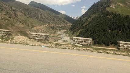 Remote mountain valley with a winding river and scattered buildings along a road.