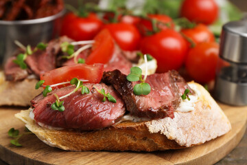 Delicious bruschettas with roast beef served on wooden table, closeup