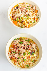 Bowl of homemade chicken noodle soup, filled with tender shredded chicken, garnished with scallion
