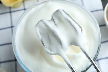 Whipped egg whites in bowl and hand mixer on table, above view