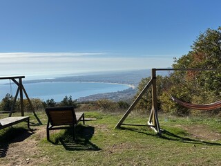 playground in the forest Beautiful scenic view with a wooden swing and bench overlooking the calm blue sea on a sunny day. Peaceful coastal landscape and clear sky. Perfect travel and relaxation conce