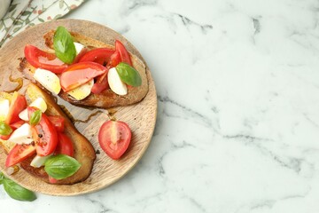 Tasty bruschettas with mozzarella cheese, tomatoes and basil on white marble table, flat lay. Space for text