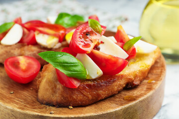 Tasty bruschettas with mozzarella cheese, tomatoes and basil on white table, closeup