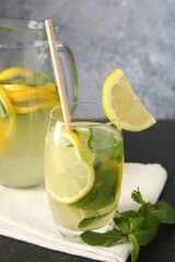 Fototapeta premium Fresh lemonade with lemon, jug and mint on black table, closeup
