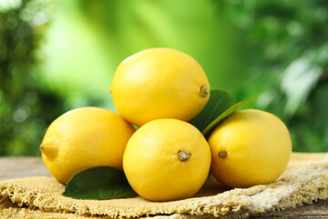 Fresh lemons with green leaves on table outdoors, closeup
