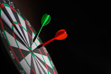 Dartboard with darts on black background, closeup. Space for text