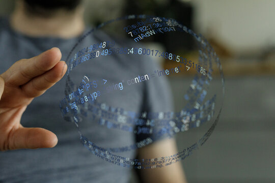 A person's hand interacting with a transparent globe overlaid with computer code, representing innovation and technology. Capturing t