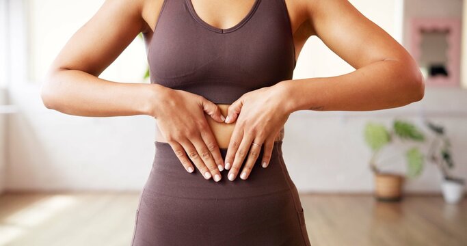 Fitness, heart hands and woman in gym with stomach, gut health and inspiration for body goals. Sport, emoji and athlete in studio with gesture, weight loss and digestive balance in wellness routine.