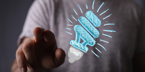 Person's hand pointing at a light bulb illustration. Represents innovation, idea, and business...