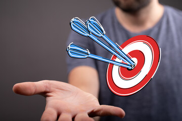 Close-up of a man's hand holding a target with arrows, representing achievement, success, and...