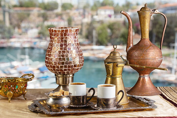 still life with eastern coffee set on table. Mediterranean Sea on a sunny summer day in the background.