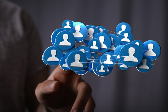 Concept image of a hand touching a network of connected people icons. Represents teamwork, communication, and social connections in a digital wo